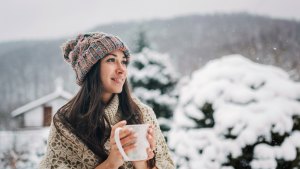 Young woman enjoying the snowy winter day with a cup of hot tea