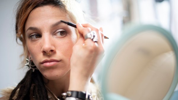 Beautiful young woman with a unique personal style putting on make-up
