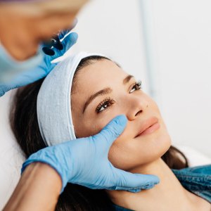 young woman is getting a rejuvenating facial injections at beauty clinic. The expert beautician is filling female wrinkles by botulinum.