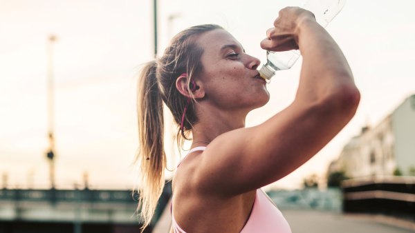 Woman after fitness workout,drinking outdoor in the city.