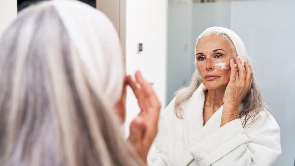 Mature woman applying face cream in bathroom