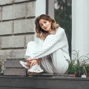 Beautiful young model girl happy and fashionable is sitting on a wooden terrace