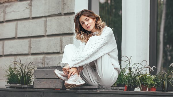 Beautiful young model girl happy and fashionable is sitting on a wooden terrace