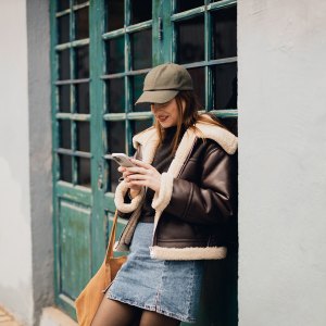 Smiling young woman using a smartphone in the city street on a lovely autumn day