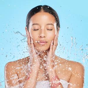 Shot of a beautiful young woman being splashed with water against a blue background