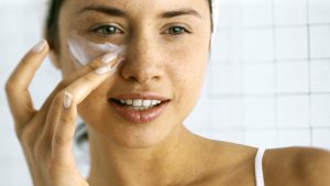 Woman applying moisturizer beneath eye