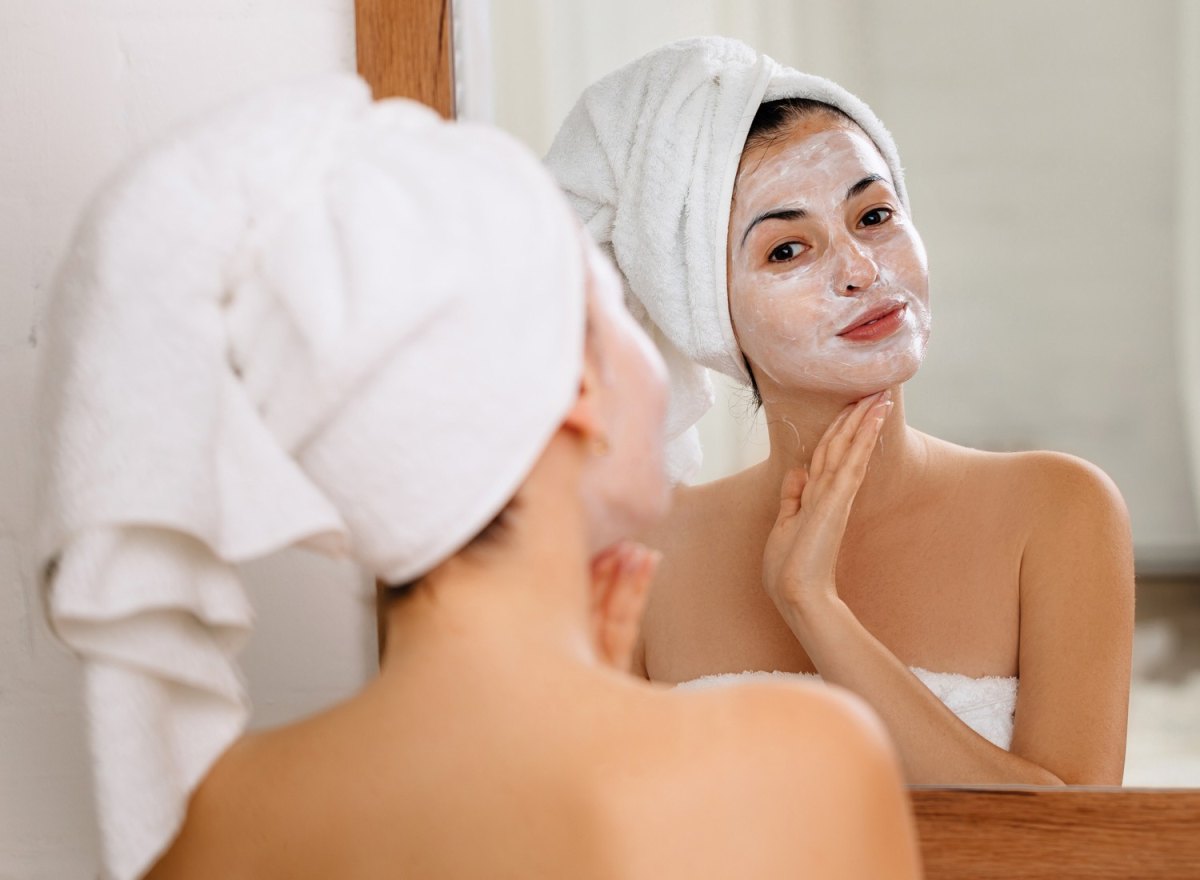 Woman applying a face mask in a mirror