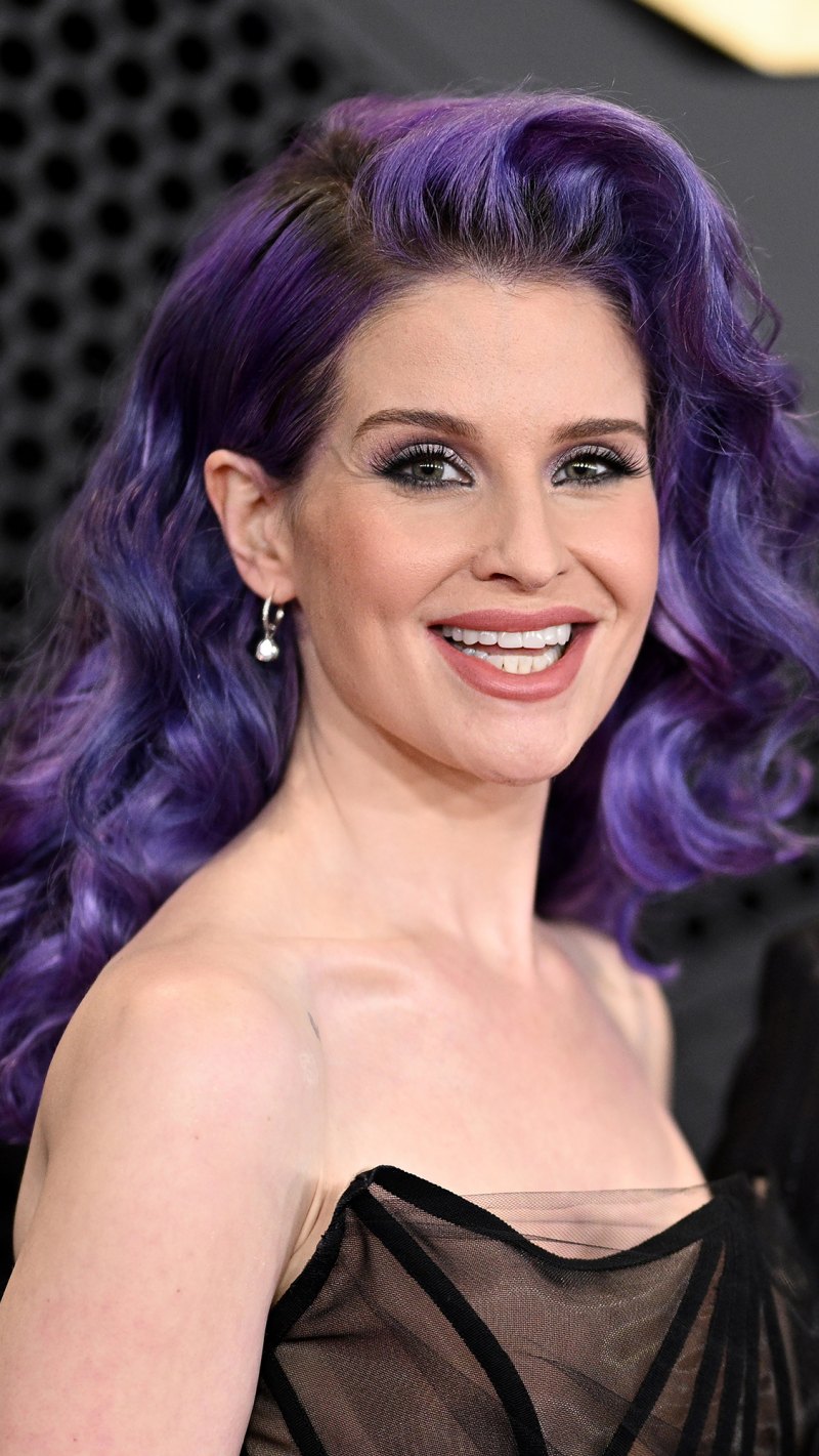 Kelly Osbourne with Curly Purple Hair Smiling and Looking at Camera in Black Top Sheer Dress