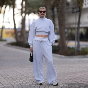 MIAMI, FLORIDA - DECEMBER 08: Lena Gercke seen wearing Saint Laurent black sunglasses, silver statement necklace, Alexander Wang light grey high neck cotton cropped jumper / sweater, Alexander Wang light grey cotton wide leg jogger pants with underwear detail, Saint Laurent black varnishes leather mini bag and Axel Arigato white leather sneakers, on December 08, 2023 in Miami, Florida. (Photo by Jeremy Moeller/Getty Images)2