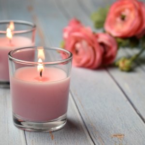 Scented pink candles with flowers in the background, close-up