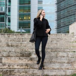 Beautiful young woman in real life using smartphone on the street