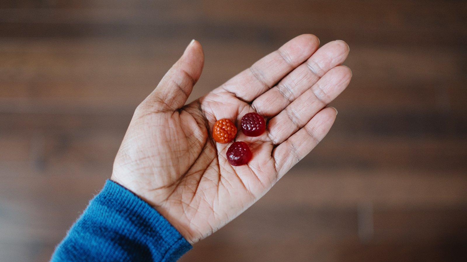 High angle view of woman's hand holding fruit-flavored gummy nutritional supplements