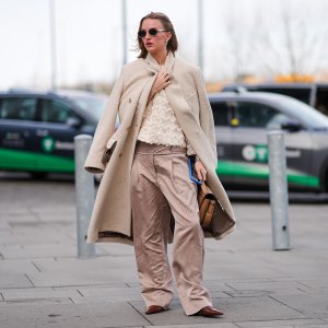 Inspiration shot: A guest wears sunglasses, a white fluffy long coat, a fluffy jacket with embroidered geometric patterns, beige palazzo flared pants , a brown leather bag, pointed shoes , outside TG Botanical, during the Copenhagen Fashion Week AW24 on February 01, 2024 in Copenhagen, Denmark. (Photo by Edward Berthelot/Getty Images)