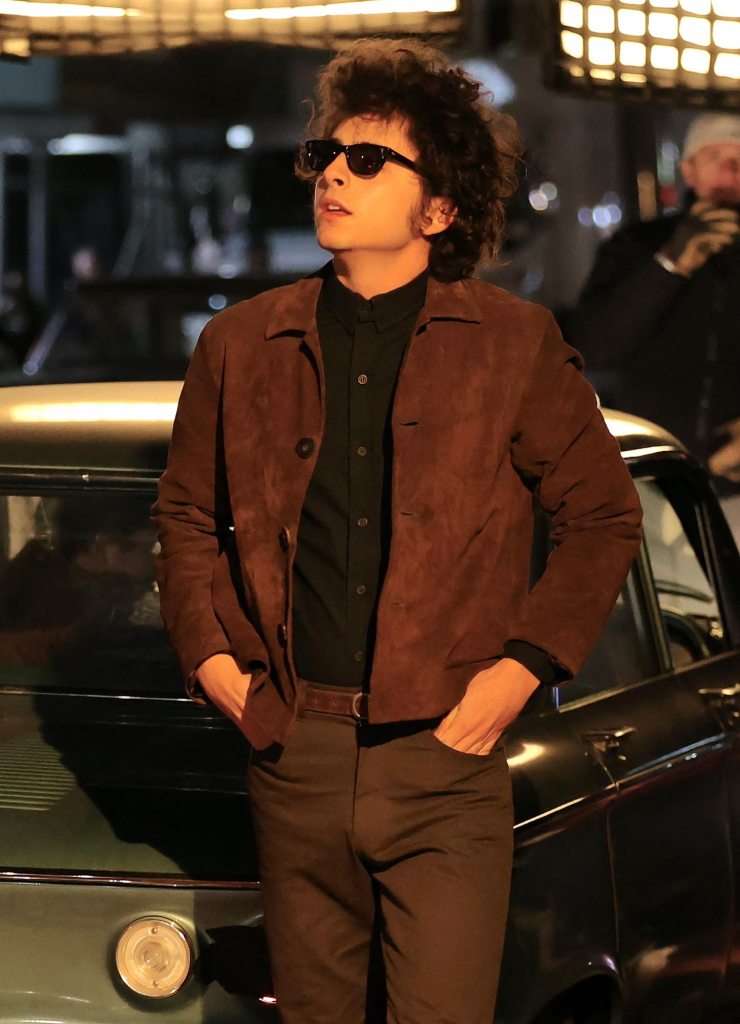 Feature Timothee Chalamet Transforms Into Bob Dylan In Iconic Brown Suede Jacket and Sunglasses