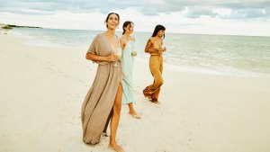 Wide shot of female friends walking on beach at tropical resort at sunset