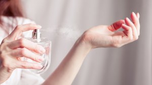 girl in a white dress sprays herself perfume on her wrist
