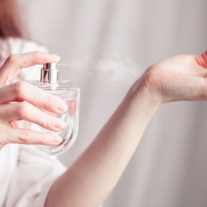 girl in a white dress sprays herself perfume on her wrist