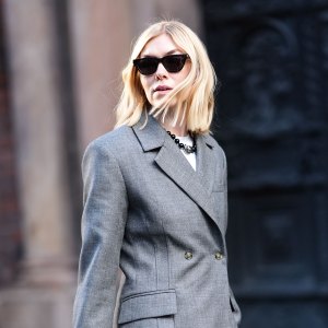 A guest wears sunglasses, a gray oversized blazer jacket , suit flared pants , shiny sequined shoes, a black woven leather Bottega Veneta bag, outside Herskind, during the Copenhagen Fashion Week FW24 on January 31, 2024 in Copenhagen, Denmark.