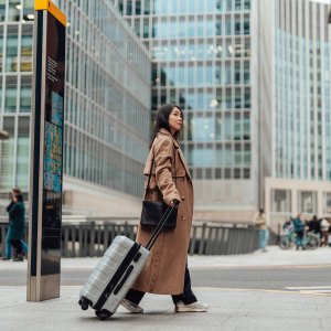 Young businesswoman carrying luggage, walking on the high street in the city.