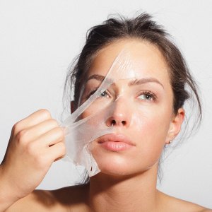 Close-up beauty portrait of a beautiful, natural young woman removing face mask.