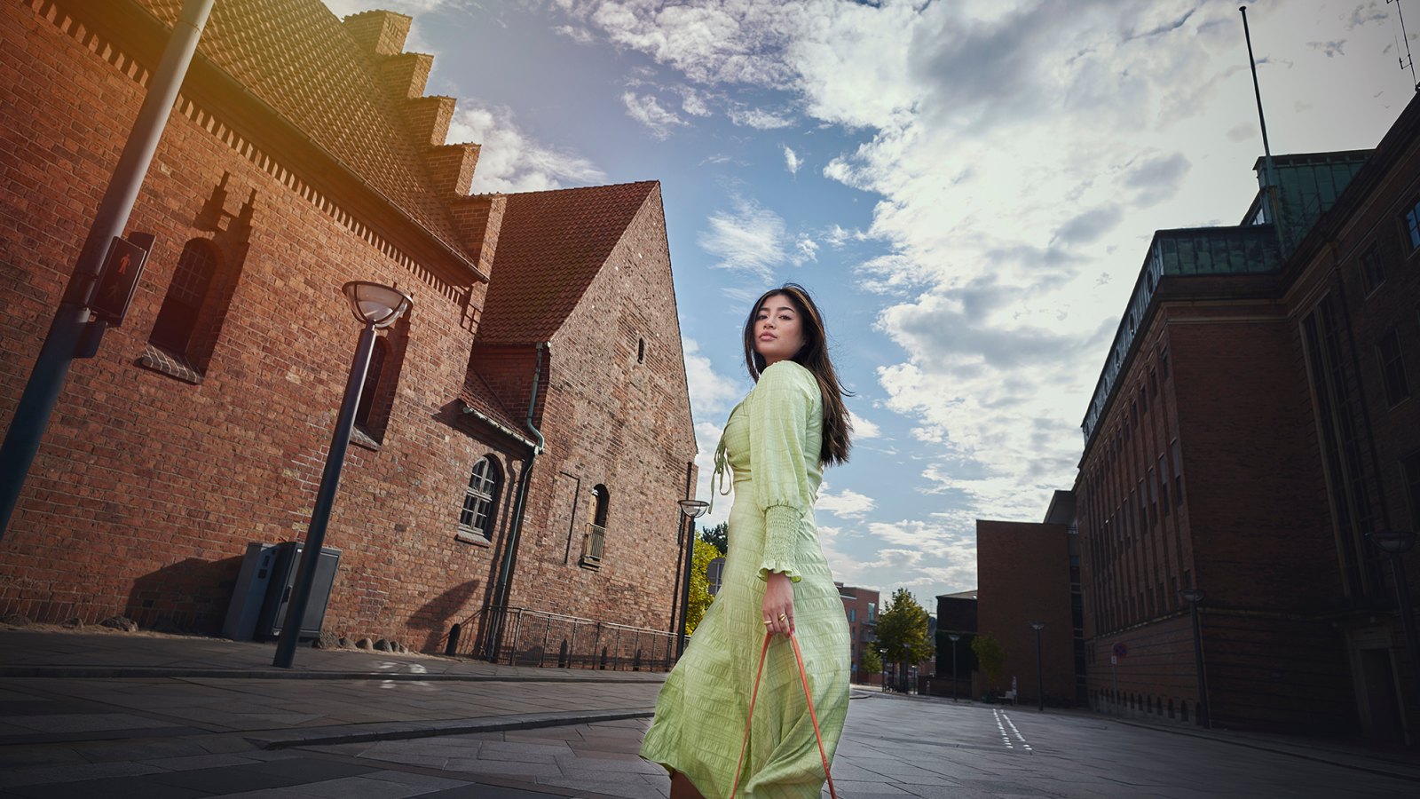 Model outdoors in city / street. Woman in green dress walking