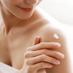 woman applying body lotion on shoulder