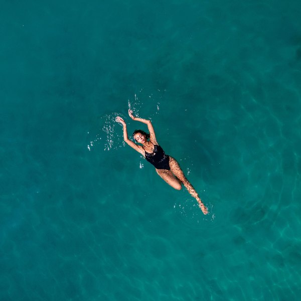 Aerial View Young Woman is Floating on Navy Blue Sea