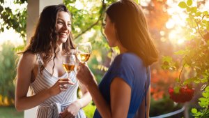 Joyful friends, drinking wine while having a casual conversation during summer garden party