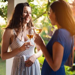 Joyful friends, drinking wine while having a casual conversation during summer garden party