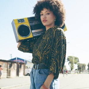 Shot of an attractive young woman listening to music on a boombox in an urban setting