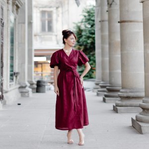 Woman in red dress is walking on street on old building background.