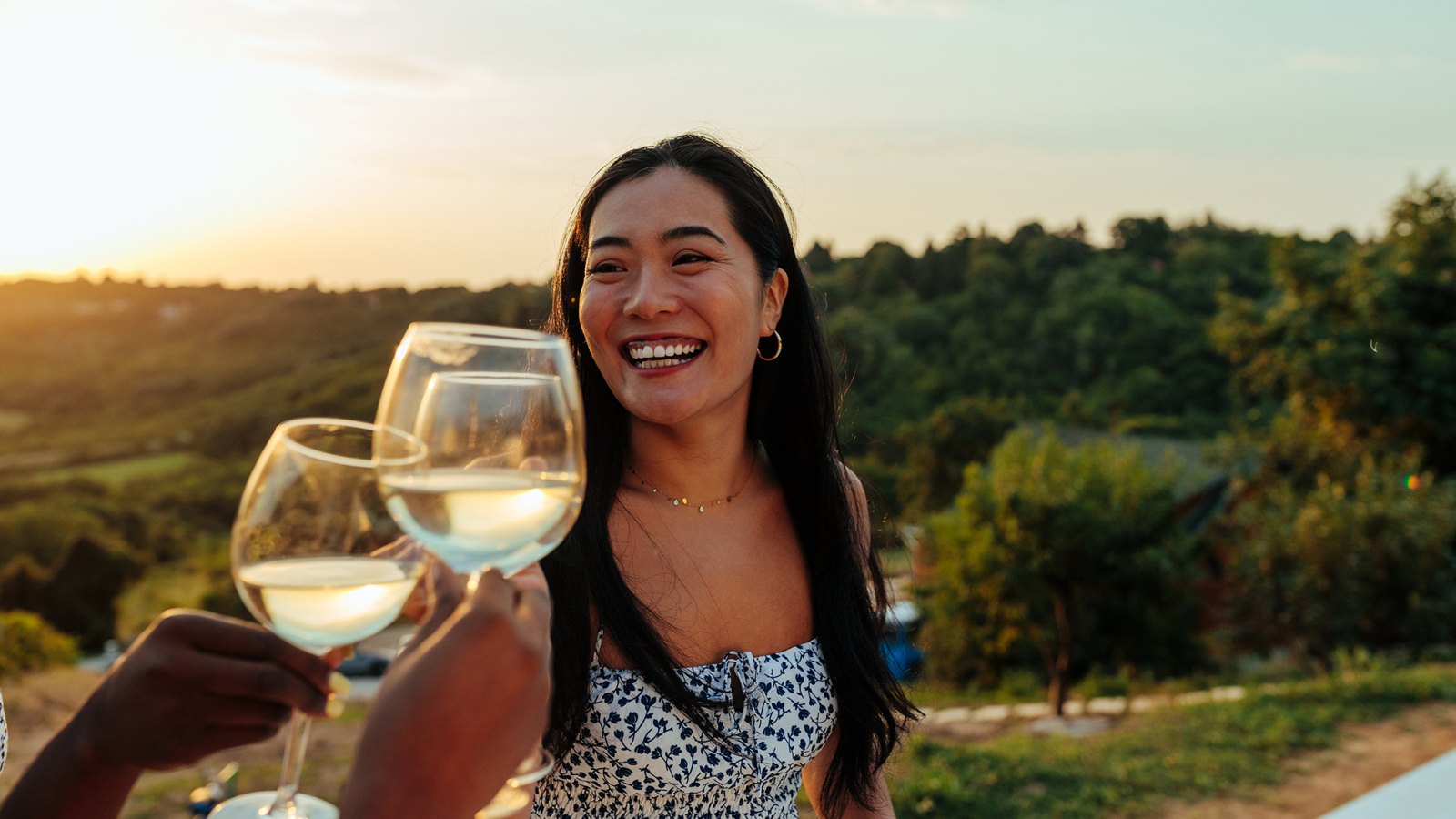 Happy woman having fun while toasting with wine at vineyard party