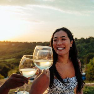 Happy woman having fun while toasting with wine at vineyard party