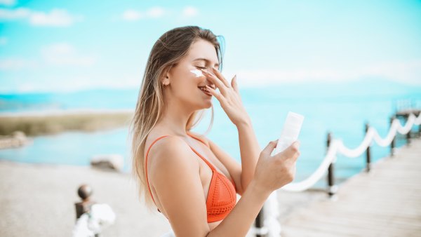 Smiling Female Beauty And Her Favorite Sunscreen At The Beach