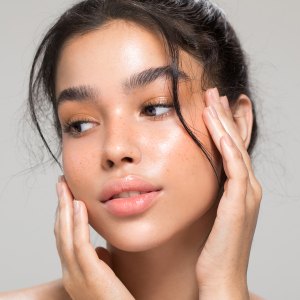 Close up studio shot of a beautiful young woman with perfect glow skin.