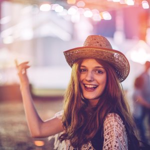 Young woman at summer festival. Dancing with her arms raised. Summertime.