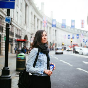 Young woman walking on the streets of central London, wearing a denim jacket and a scarf.