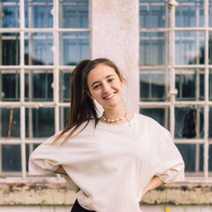 Young fashionable woman with ponytail wearing property released handmade craft designer T-Shirt Standing looking towards the Camera. Majestic industrial Window in the background. Millennial Generation Girl Young Fashion Design Portrait.