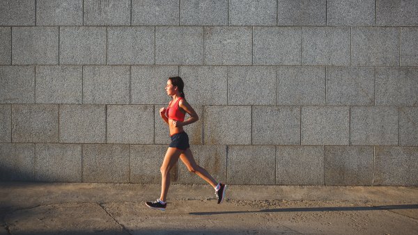 woman working out in an urban setting, running along stone wall