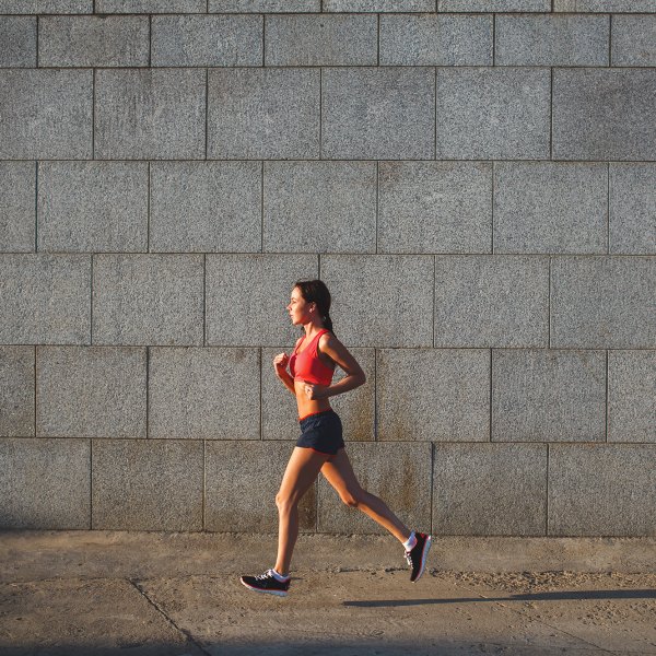 woman working out in an urban setting, running along stone wall