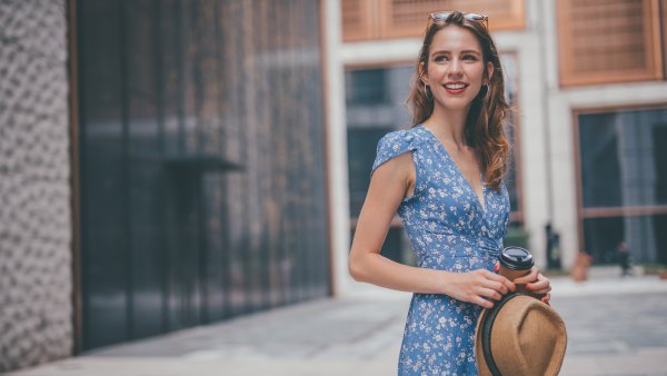 One woman, cute young woman in city, holding a coffee cup.