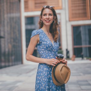 One woman, cute young woman in city, holding a coffee cup.
