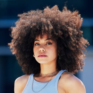 Portrait, fashion and attitude with a black woman in the city, outdoor on a bridge during a summer day. Street, style or urban and an attractive young female posing outside with an afro hairstyle