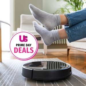 Young woman lift up the feet for letting robotic vacuum cleaner pass though