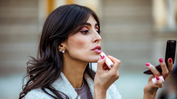 Portrait of mature beautiful woman using red lipstick outdoors . Make up and lifestyle concept