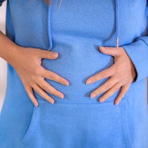 woman having abdominal bloating, overeating, round tummy close up macro