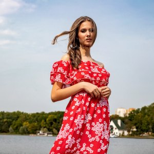 Portrait of a beautiful young brown-haired girl with long hair in a red dress on a lake background. Belarus