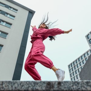 Low angle view with a happy millennial woman, dressed in a pink sport outfit smiling and raising the arms.
