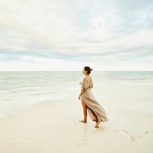 woman walking on beach in beige dress