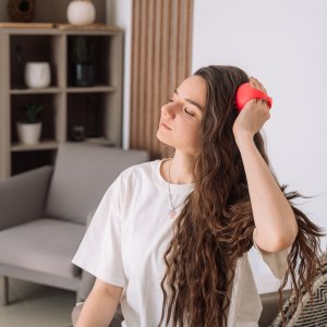 Lady takes care of scalp by doing massage with scalp massager.
